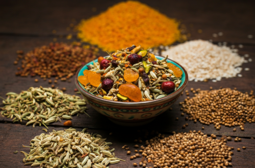 A feature image showing colorful mukhwas ingredients on a rustic surface with a bowl of mixed mukhwas in the center.