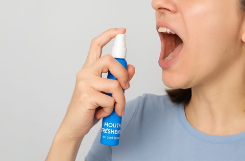 Person using an instant mouth freshener spray for fast bad breath relief
