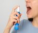 Person using an instant mouth freshener spray for fast bad breath relief